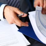 Male arm in suit offer insurance form clipped to pad and silver pen to sign closeup. Strike a bargain, driver money loss prevention, secure road trip, harmless drive idea, owner protective concept